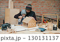 Father teaching son woodworking with birdhouse project 130131137