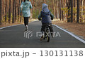 Parent jogging with child biking in forest 130131138