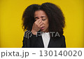 Stressed woman with headache pressing her face on yellow 130140020