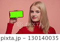 Disapproving woman showing phone with green screen 130140035