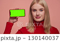 Confident woman holding smartphone with green screen 130140037