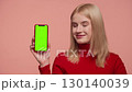 Smiling woman showing green screen phone with OK gesture 130140039