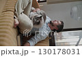 Man relaxing on sofa and petting his cat 130178031