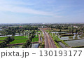 A train track surrounded by palm trees and ponds, with an overpass in the distance, on a clear day. 130193177