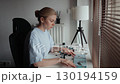Female arranging colorful construction blocks, following precise instructions while seated at home workspace, concentrating on assembly process. Female constructing colorful plastic building blocks 130194159