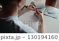 Over shoulder shot: woman carefully assembling intricate plastic model at home, following detailed instructions with precision and focused concentration. Woman building detailed plastic model 130194160
