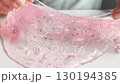 A woman or teenage girl relieves stress by playing with pink slime, stretching and squeezing it on a white table for relaxation, fun, and sensory activity 130194385