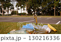 A close-up shot of an activist using tongs to collect garbage in an urban area. Plastic garbage and a discarded banana skin are visible. 130216336