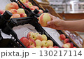 Close-up of a woman selecting red apples in a supermarket. The woman's hand holding a red apple in the grocery store. 130217114