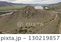 Rocky landscape with winding paths near a river and mountains in background 130219857