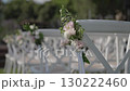 White chairs decorated with flowers in front of wedding chuppah in garden. 130222460