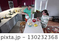 Standing at kitchen island man pours coffee into cup while his wife sits in front waiting for her drink as table holds bread butter and bowl. 130232368