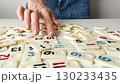 A woman hands sort domino-like tiles with numbers from a board game on a white table, preparing for play, strategy, and entertainment in leisure time 130233435