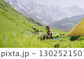 Woman on backpacking trip cooks outdoors with mini gas stove in mountain meadow, makes coffee in pot, turns off burner. Scenic travel destination. Outdoor adventure in nature, slow motion. Slowmo 130252150