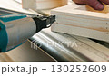 Close up view of a carpenter using a nail gun to nail a piece of wood. 130252609