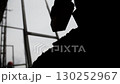 Silhouette of construction worker laying brick at building site 130252967