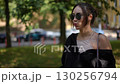 A stylish and chic woman wearing sunglasses enjoys her time outdoors on a sunny day 130256794