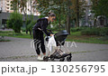 A Young Woman is Joyfully Strolling through the Park with a Baby Stroller in the Afternoon 130256795