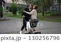 Two Women Engaging in a Friendly Interaction with a Baby Stroller in a Park Setting 130256796