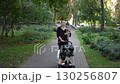 A woman is leisurely walking through a beautiful park with her dog and a stroller in tow 130256807