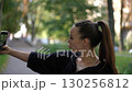 A Young Woman is Taking a Selfie in a Beautiful Park Setting with Joyful Vibes all around 130256812