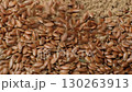 Whole fax seeds pour on pile of flaxseed meal flour, slow motion 130263913