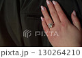 An Elegant Hand Displaying a Ring on a Beautiful Dark Fabric Background for Added Contrast 130264210