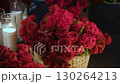An exquisite arrangement of beautiful red flowers beautifully complemented by glowing candles 130264213