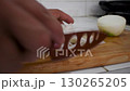 Chopping Onion on Cutting Board, Hand Cutting Onion with Knife, Preparing Vegetables for Cooking 130265205