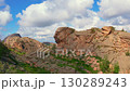Rock formation resembling a human face among mountain ridges and greenery 130289243