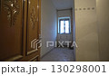 Carved door opens corridor with plastered walls and window 130298001