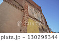 Damaged wall with falling bricks contrasts with clear sky 130298344