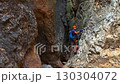 Climber on via ferrata trail, crossing a deep canyon. 130304072