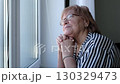 Thoughtful elderly woman staring out the window. Symbolizes nostalgia, inner strength, and hope for new beginnings. 130329473
