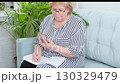 Senior woman in glasses looking at her phone with a pen in hand. Represents learning, online research, and adapting to new technologies. 130329479