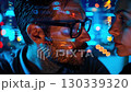 A focused duo exploring digital connections with technology illuminating their faces in a captivating cybernetic environment. 130339320