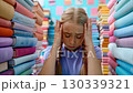 A young girl appears overwhelmed and frustrated amidst a colorful array of books, highlighting her struggle with academic pressure and the weight of expectations. 130339321