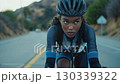 A focused cyclist navigating a winding road during a serene ride through beautiful landscapes, embodying determination and the spirit of adventure. 130339322