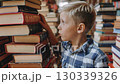 A curious child stands between towering stacks of books, captivated by the world of literature and imagination that surrounds him in a cozy library. 130339326