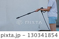 Young woman wash house wall with pressure washer. 130341854