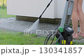 Young woman wash clean path with pressure washer in the backyard. 130341857