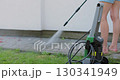 Young woman girl wash dirty path with pressure washer in the backyard. 130341949