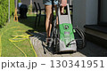 Woman pulling a high-pressure washer in the backyard of a house. 130341951