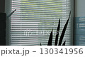Close up woman opens blinds in dark room, stretches. Sunlight behind horizontal blinds. Metal blinds that open on large windows in the interior. 130341956