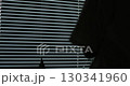 Close up woman opens blinds in dark room, stretches. Sunlight behind horizontal blinds. Metal blinds that open on large windows in the interior. 130341960