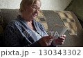 Old woman with wrinkled face hold stack of vintage photographs. Black white photo with nostalgic touch, evoking cherished memories. Lonely elderly people in nursing home. Sitting on couch at home 130343302