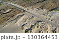 Excavator clearing road from sand in desert 130364453