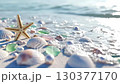 Starfish rests among various shells and gems on sandy beach. Gentle waves lap at shore, creating peaceful atmosphere. Summer light enhances colors and creates tranquil setting 130377170