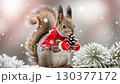 A charming squirrel dressed in a red scarf is happily clutching a pine cone in a snowy environment. Delicate snowflakes gently fall around as greenery adds to winter beauty 130377172