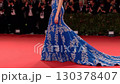 Stylish individual walks gracefully on red carpet at significant film event wearing a stunning blue gown with exquisite details. Crowd captures every moment with excitement 130378407